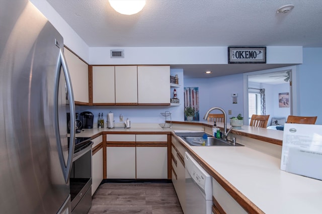 kitchen featuring visible vents, a sink, white cabinetry, stainless steel appliances, and light countertops