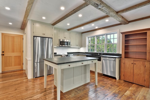 kitchen with a kitchen bar, light wood-type flooring, a kitchen island, stainless steel appliances, and white cabinets