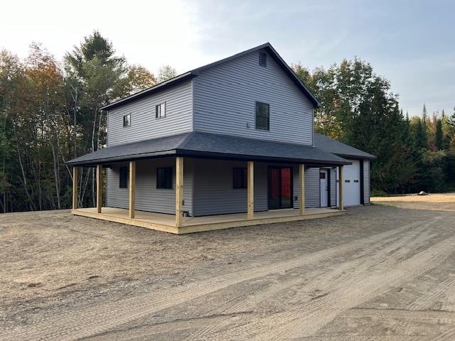 farmhouse inspired home with a porch and a garage