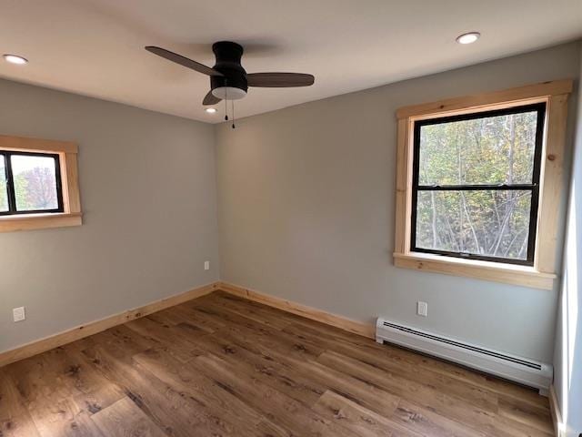 unfurnished room featuring hardwood / wood-style flooring, ceiling fan, and baseboard heating