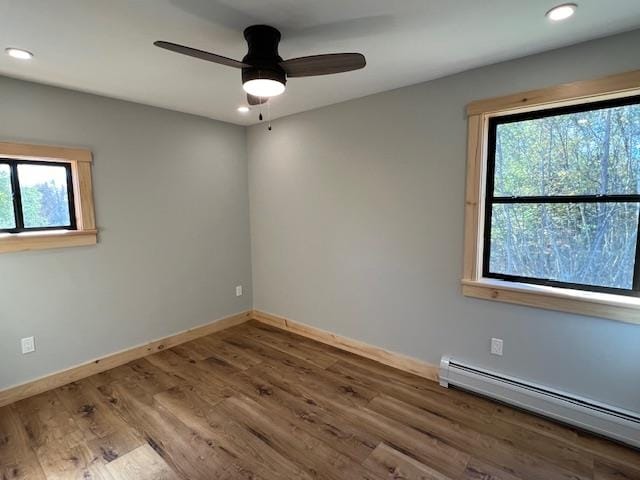 unfurnished room featuring wood-type flooring, a wealth of natural light, and a baseboard radiator