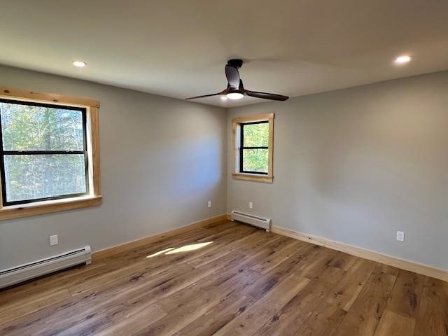 spare room with hardwood / wood-style floors, a baseboard radiator, and ceiling fan