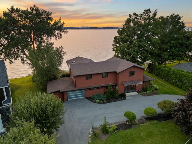 aerial view at dusk featuring a water view