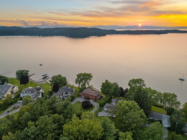 aerial view at dusk featuring a water and mountain view