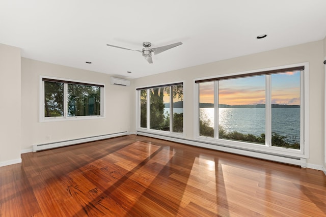 unfurnished room with wood-type flooring, an AC wall unit, a baseboard radiator, a water view, and ceiling fan