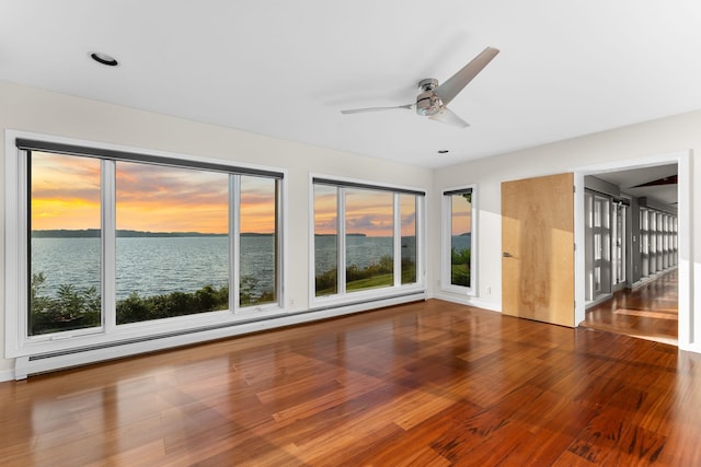 spare room with wood-type flooring, a water view, ceiling fan, and baseboard heating