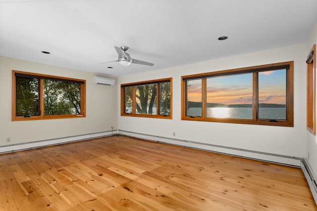 spare room with light hardwood / wood-style flooring, ceiling fan, a wall mounted air conditioner, and a wealth of natural light