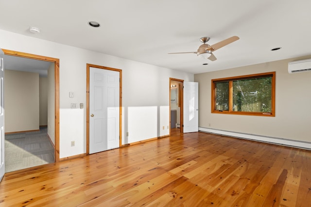 unfurnished bedroom featuring a baseboard heating unit, light hardwood / wood-style floors, ceiling fan, and a wall mounted air conditioner