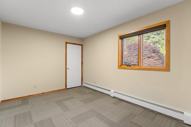 spare room featuring light carpet and a baseboard heating unit