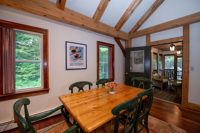 dining area featuring a baseboard radiator, a wealth of natural light, wood-type flooring, and vaulted ceiling with skylight