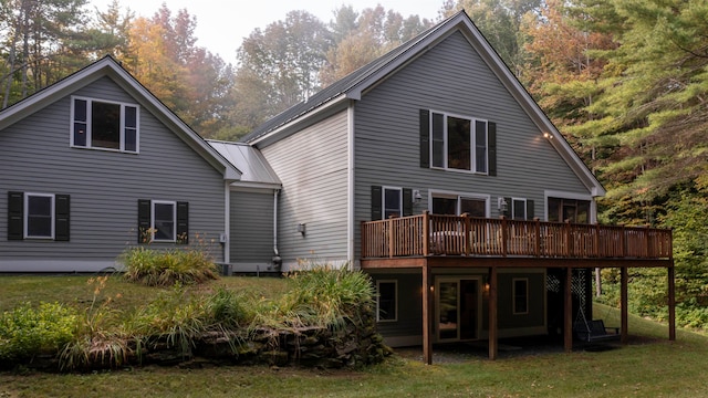 back of property with a deck and a yard