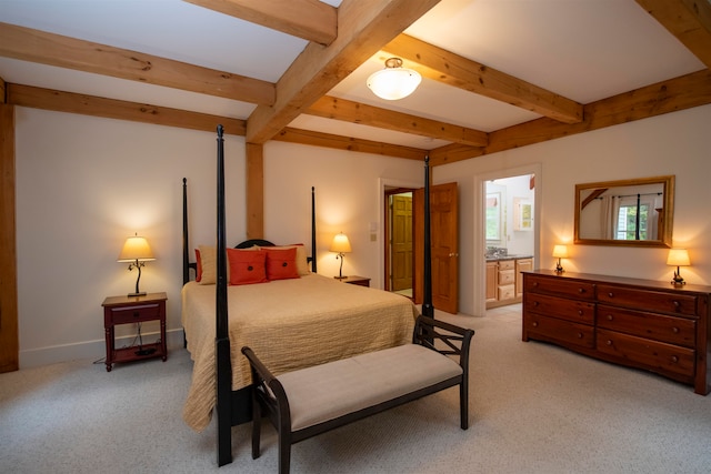 bedroom with light carpet, beamed ceiling, and ensuite bath