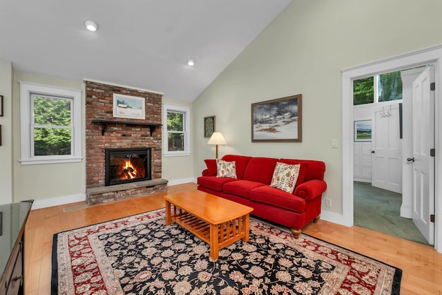 living room featuring a brick fireplace, hardwood / wood-style floors, and high vaulted ceiling