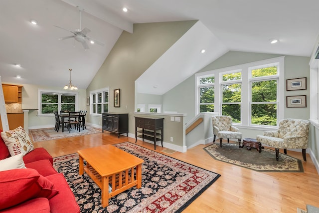 living room featuring ceiling fan with notable chandelier, light hardwood / wood-style floors, and lofted ceiling with beams