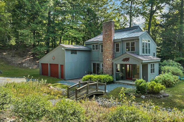 rear view of house featuring a garage and an outbuilding