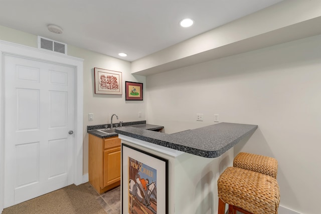 kitchen featuring a breakfast bar, wine cooler, sink, kitchen peninsula, and light tile patterned floors