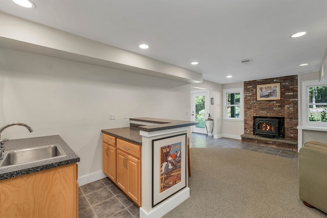 kitchen featuring a wealth of natural light, kitchen peninsula, a fireplace, and sink