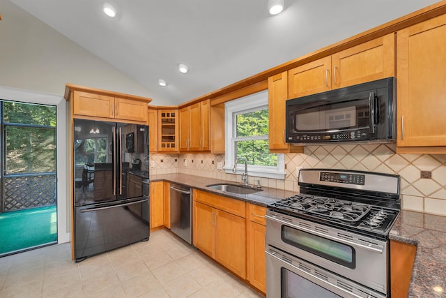 kitchen with sink, lofted ceiling, decorative backsplash, black appliances, and dark stone countertops