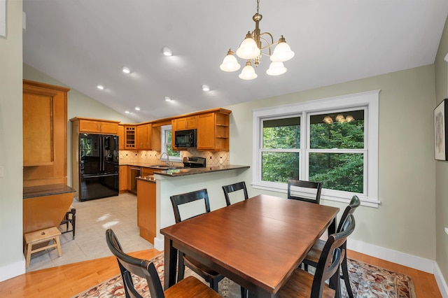 dining area featuring light hardwood / wood-style floors, vaulted ceiling, an inviting chandelier, and sink