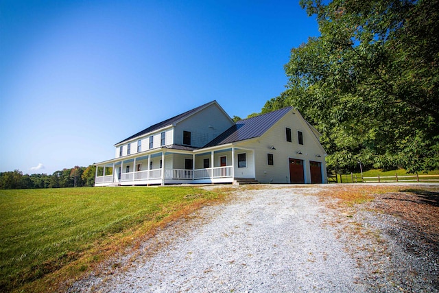 farmhouse inspired home with a front lawn, a porch, and a garage