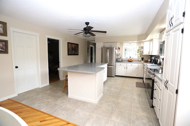 kitchen featuring light wood-type flooring, a center island, white cabinets, appliances with stainless steel finishes, and ceiling fan