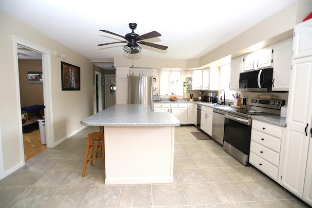 kitchen featuring sink, white cabinets, a kitchen island, stainless steel appliances, and ceiling fan