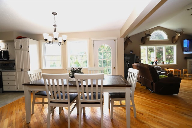 dining space featuring an inviting chandelier, lofted ceiling, and light hardwood / wood-style floors