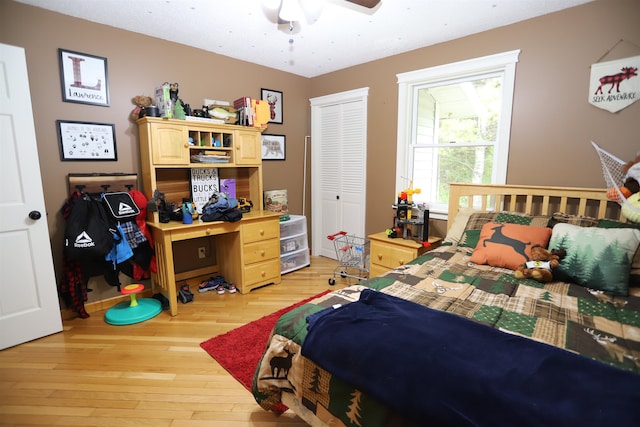 bedroom with ceiling fan, light wood-type flooring, and a closet