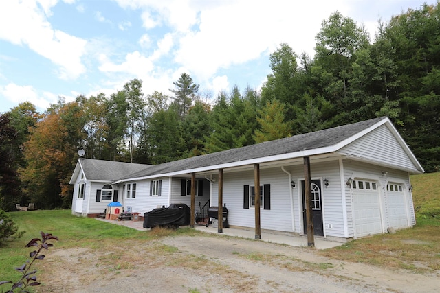 single story home featuring a garage, a porch, and a front lawn