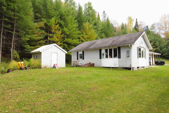 rear view of house featuring a lawn and a storage unit