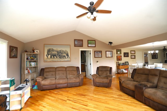 living room with ceiling fan with notable chandelier, light wood-type flooring, and vaulted ceiling