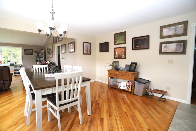 dining room featuring an inviting chandelier, hardwood / wood-style flooring, and lofted ceiling