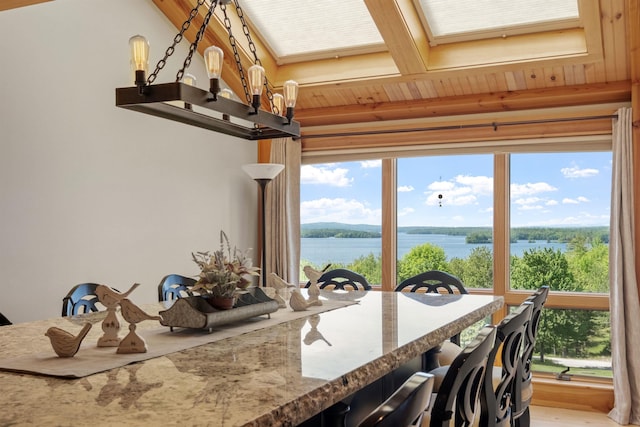 dining area featuring a skylight, light wood-type flooring, and a water view