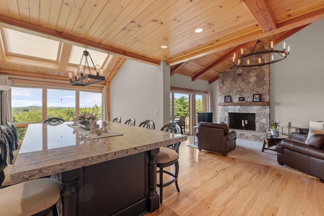 dining room featuring lofted ceiling with beams, a fireplace, wooden ceiling, light hardwood / wood-style flooring, and a notable chandelier