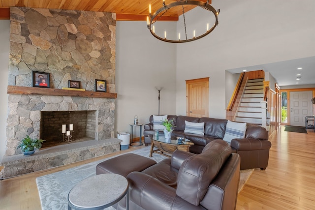 living room featuring light wood-type flooring, a chandelier, high vaulted ceiling, a stone fireplace, and wooden ceiling