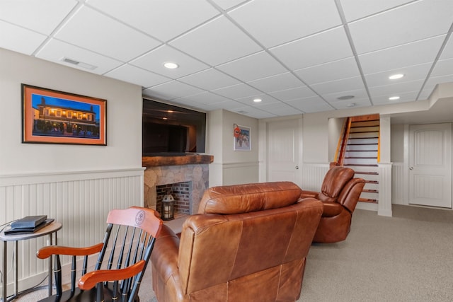 living room with light carpet, a fireplace, and a paneled ceiling