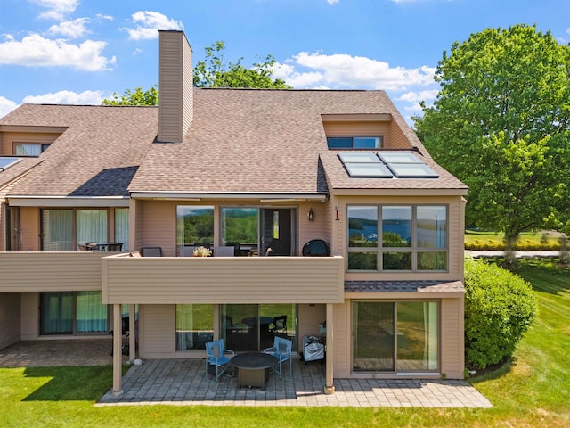 back of property featuring a patio, a balcony, and a lawn