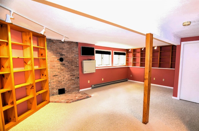 unfurnished living room featuring a baseboard heating unit, track lighting, a textured ceiling, carpet floors, and a fireplace