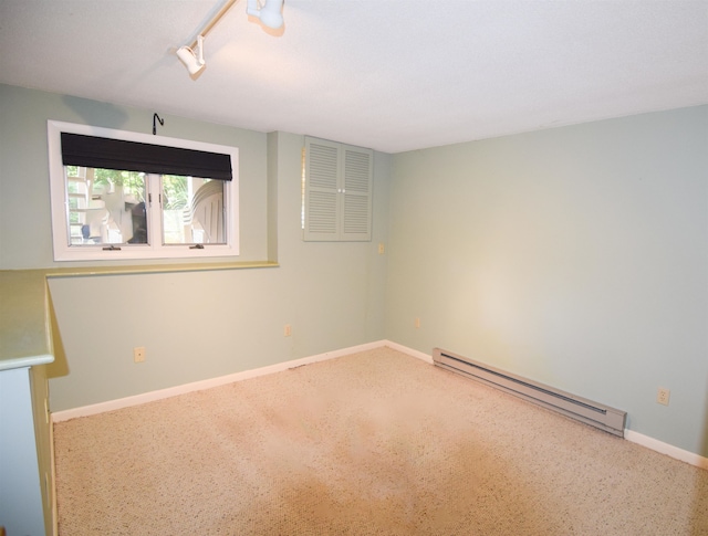 carpeted empty room with track lighting and a baseboard radiator