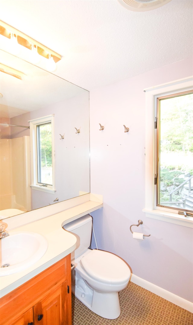 bathroom with toilet, walk in shower, vanity, and tile patterned floors