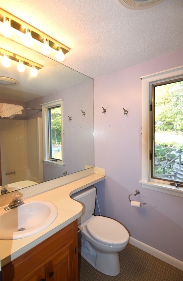 bathroom with tile patterned floors, toilet, vanity, a textured ceiling, and walk in shower