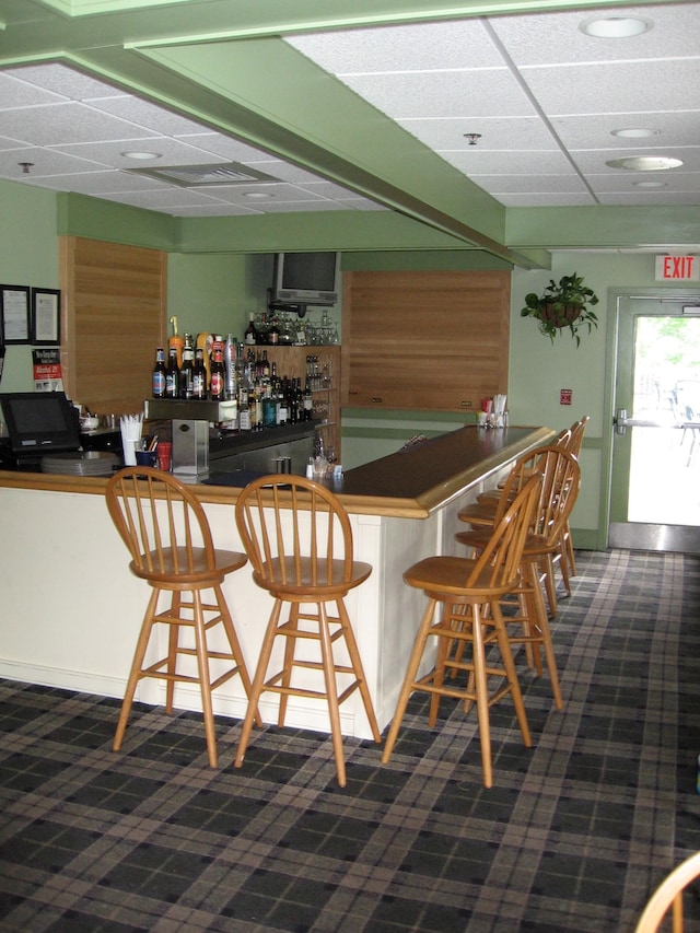 bar featuring a drop ceiling and dark colored carpet