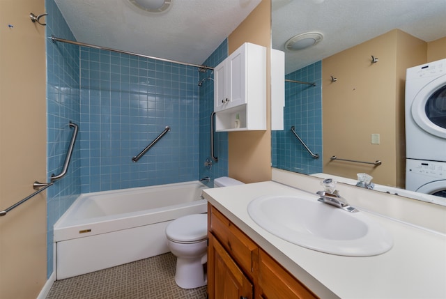 full bathroom featuring a textured ceiling, toilet, vanity, stacked washer / drying machine, and tiled shower / bath combo