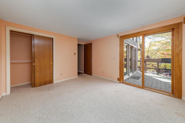 unfurnished bedroom featuring a closet, light carpet, and access to outside