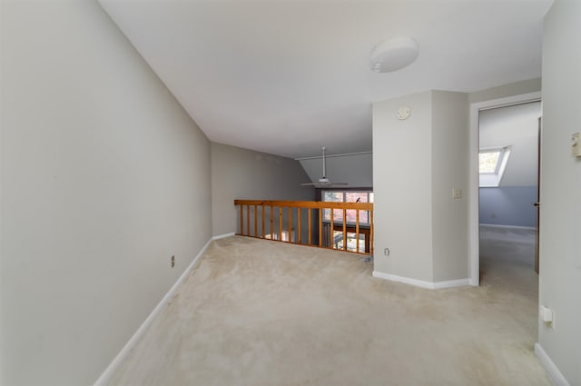 spare room featuring light carpet and vaulted ceiling with skylight