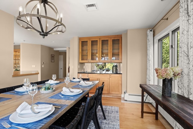 dining room with a notable chandelier, light wood-type flooring, and a baseboard heating unit