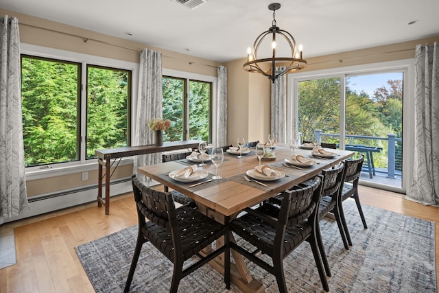 dining area featuring a baseboard heating unit, a wealth of natural light, a notable chandelier, and light wood-type flooring