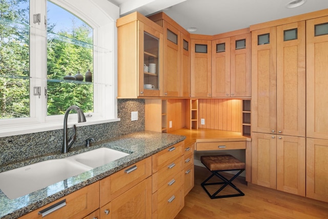 kitchen featuring tasteful backsplash, dark stone countertops, sink, and light hardwood / wood-style floors