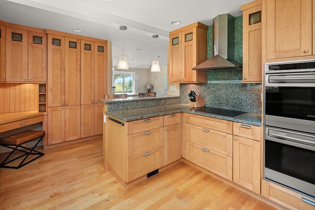 kitchen with hanging light fixtures, light hardwood / wood-style floors, kitchen peninsula, stainless steel double oven, and wall chimney range hood