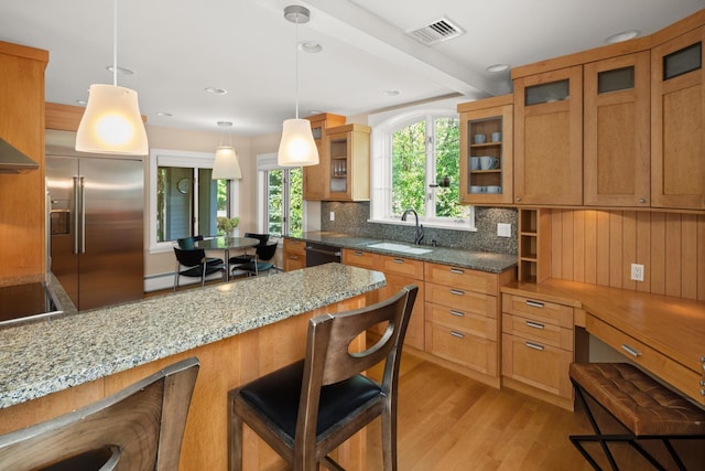 kitchen featuring a kitchen bar, light hardwood / wood-style flooring, stainless steel built in fridge, and sink